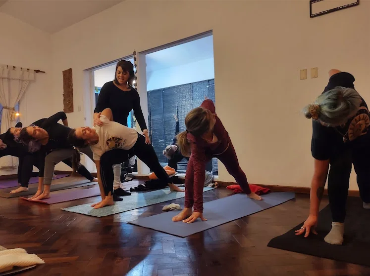Loretta Milessi acompaña y corrige a una alumna durante una postura en Yoga Shala.