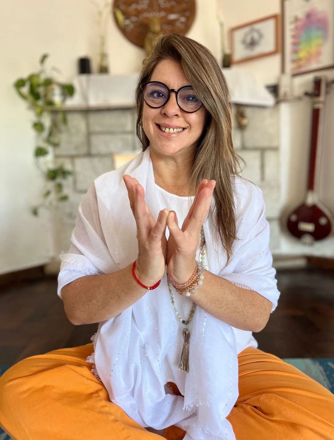 Loretta Milessi vestida de blanco, realizando un mudrā en Yoga Shala.