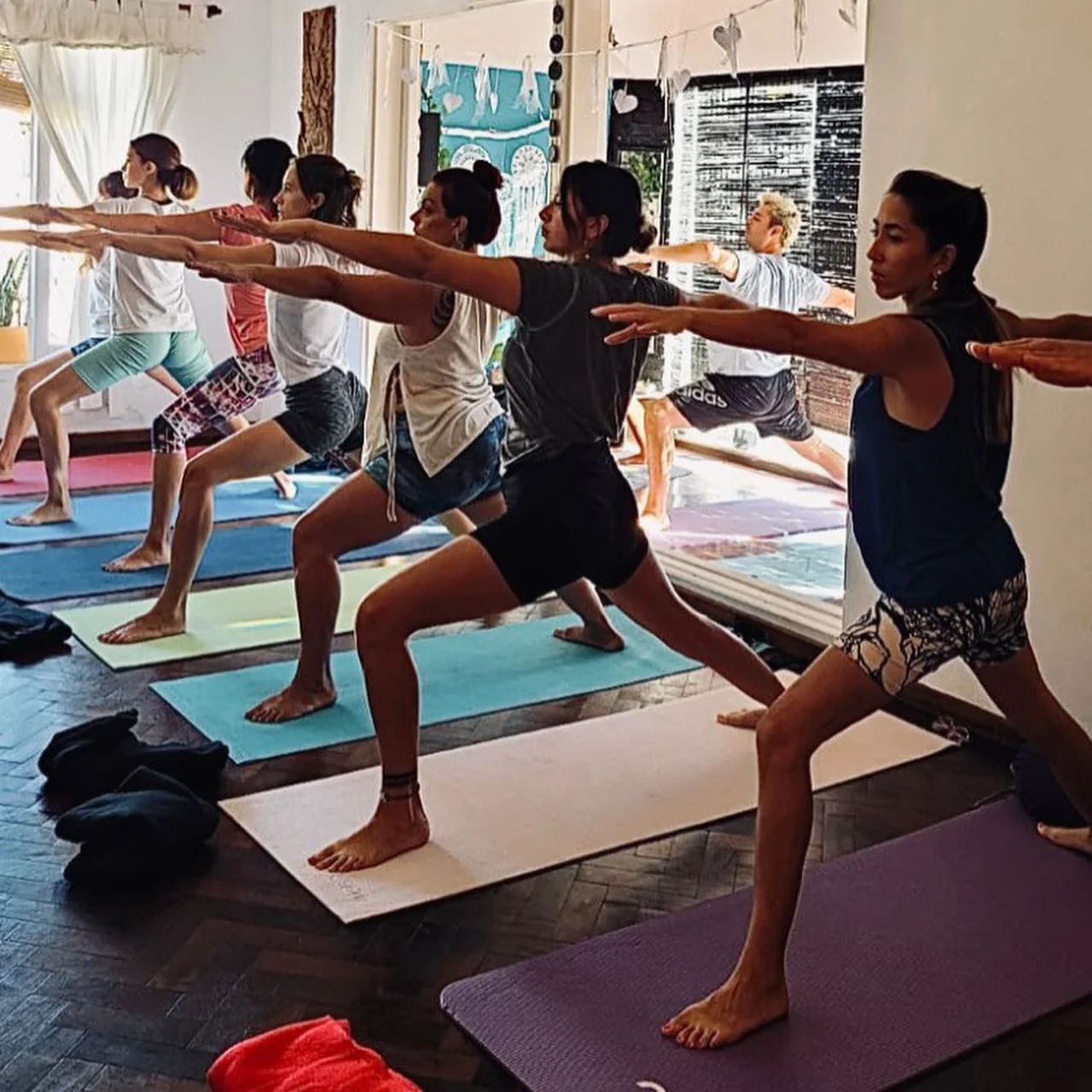 Grupo practicando una postura de pie con los brazos extendidos en Yoga Shala.